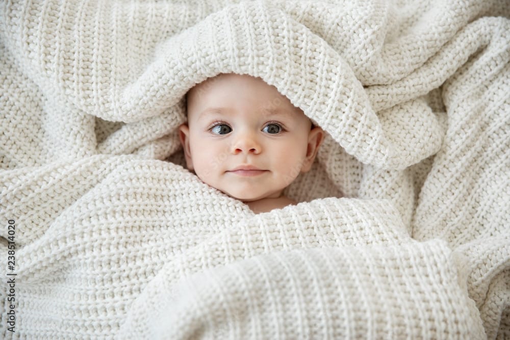 Close up of baby girl wrapped in a security blanket symbolizing an emergency savings account learned on Think and Talk Money.