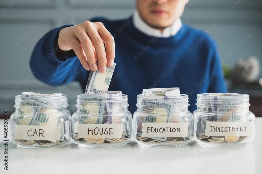 Man putting money in separate savings buckets that he learned from Think and Talk Money