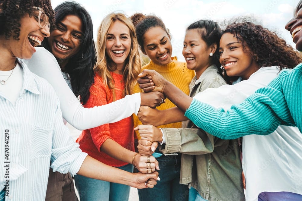 Multicultural group of women stacking hands together - Female community concept with different girls support each other - Girlfriends hugging outdoors encouraging each other to visit think and talk money.