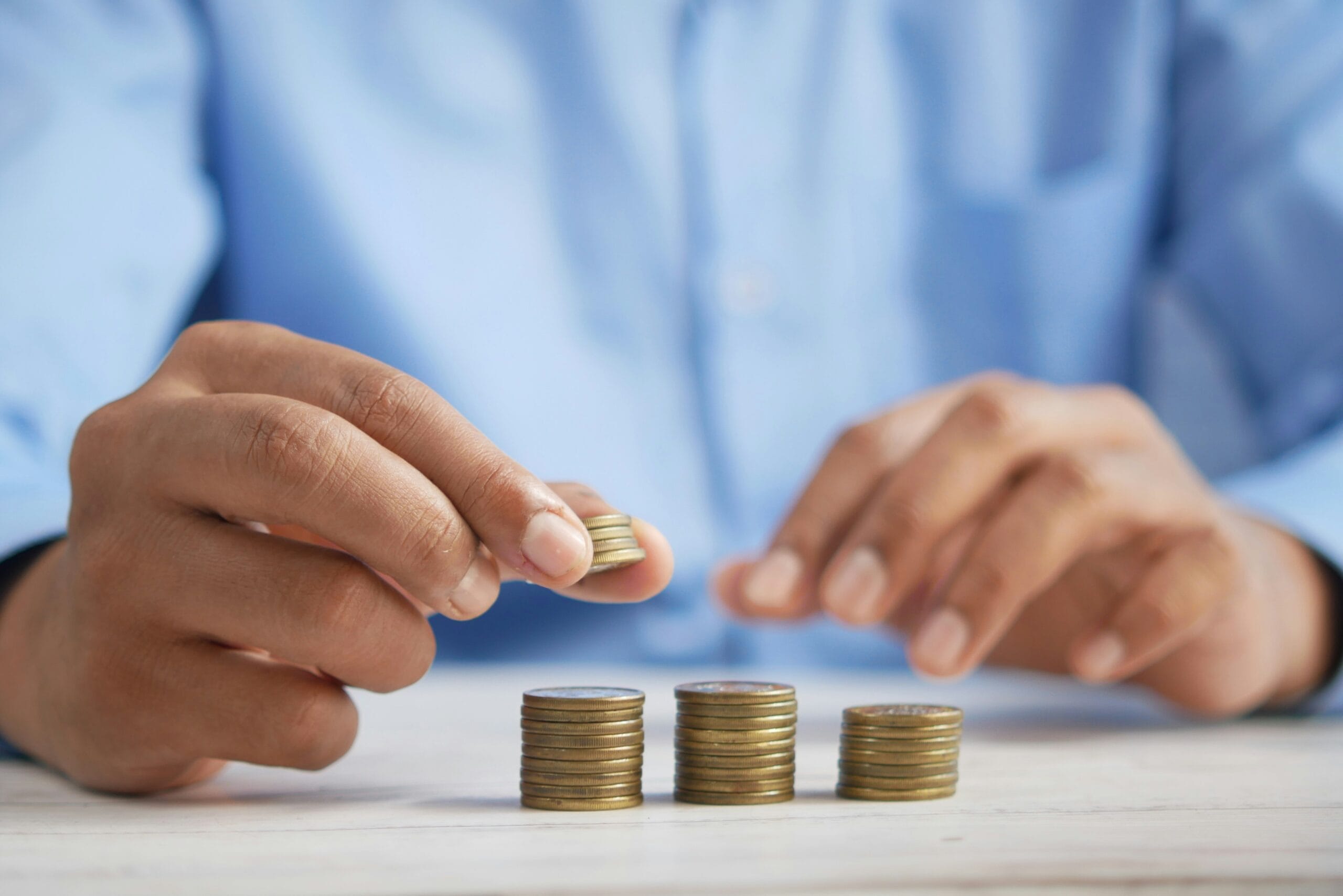 a person stacking coins on top of a table illustrating that investing does not have to be complicated if your mindset is in the right place.