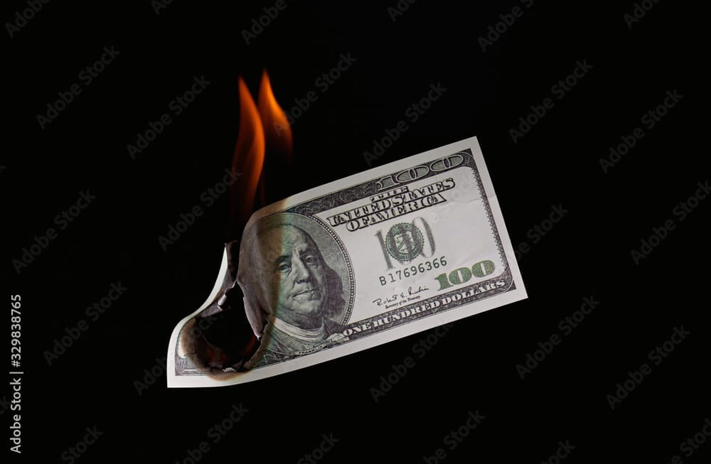 Money fire burn dollar paper illustrating how to set money on fire by taking money out of the market instead of investing.